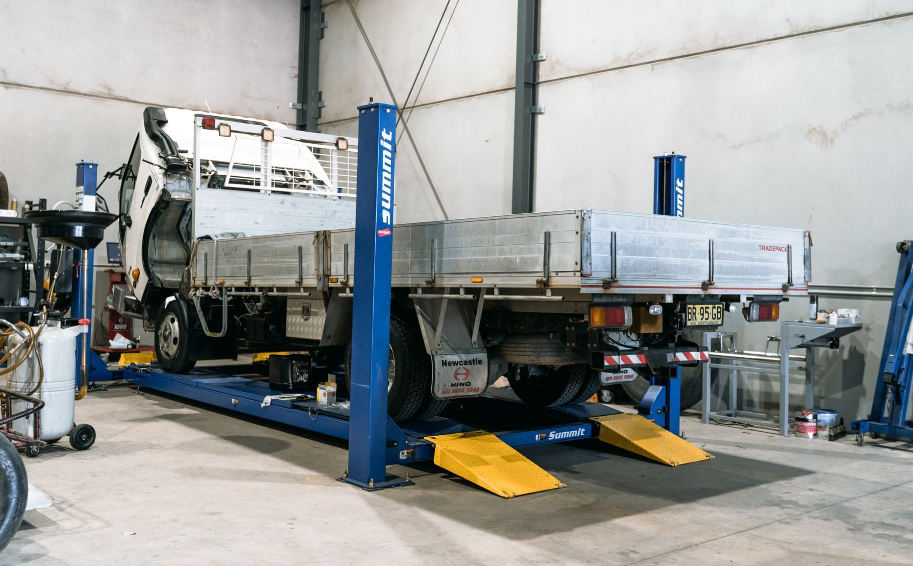 Truck on a lift in a garage, with wheels raised and ramps in an auto repair workshop — Gardiner Automotive & Performance in Rutherford, NSW