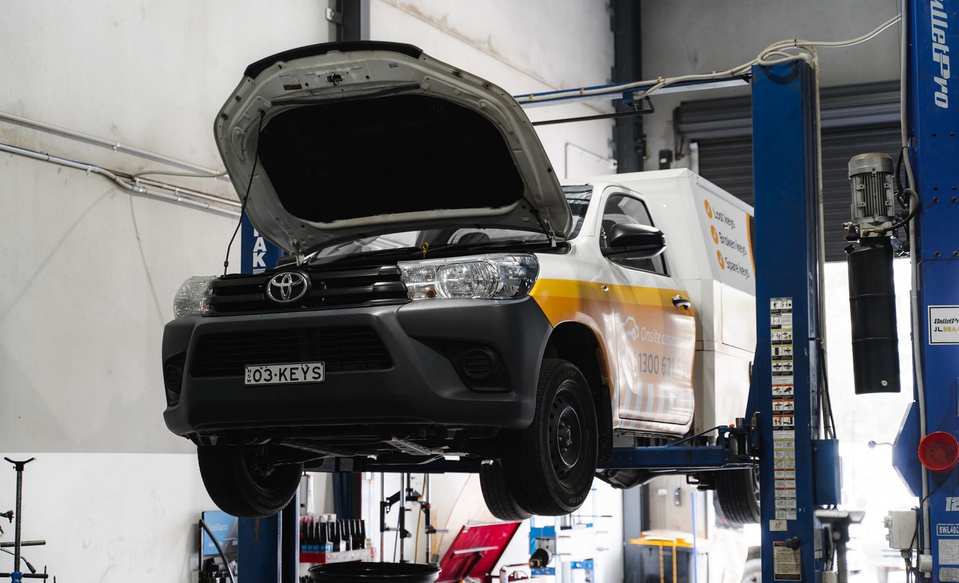 White Toyota Pickup Lifted in A Service Bay — Gardiner Automotive & Performance in Rutherford, NSW