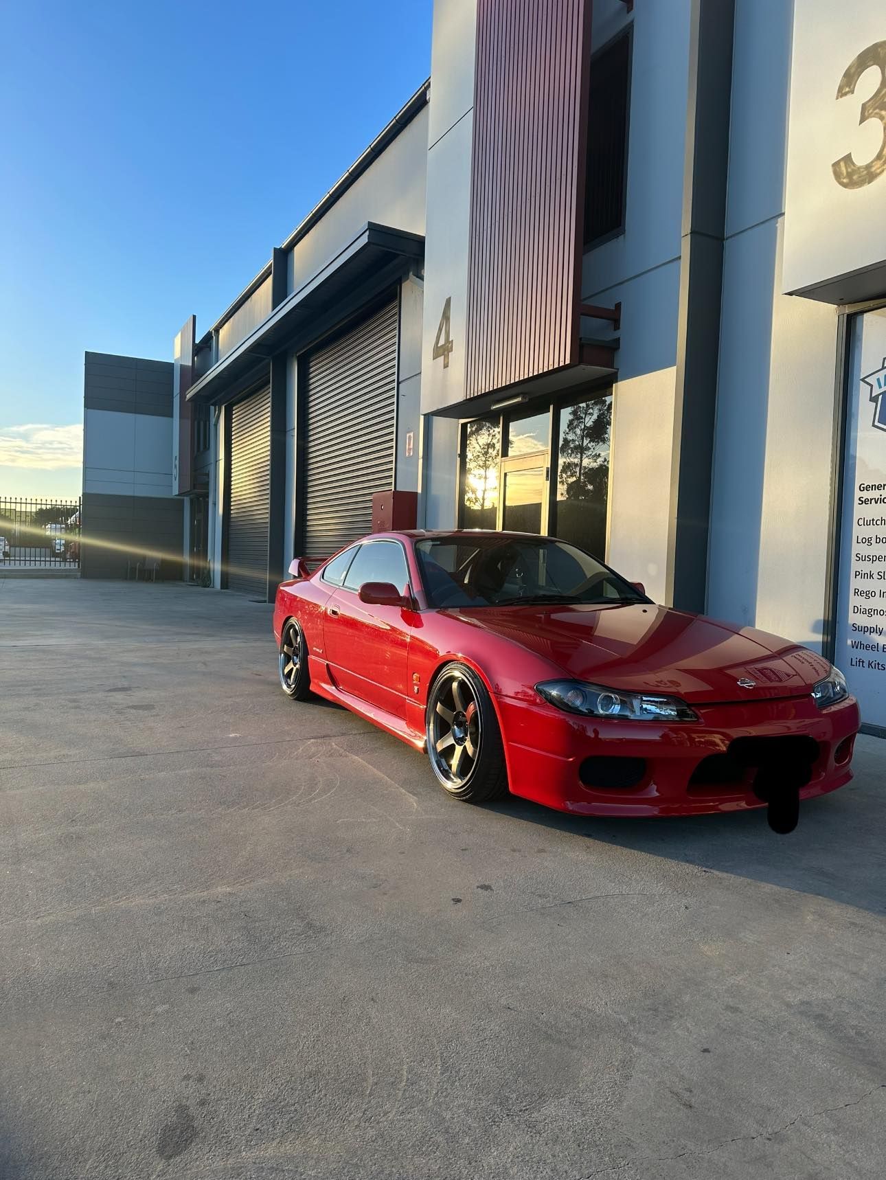Red Sports Car Parked Beside an Industrial Building at Sunset — Gardiner Automotive & Performance in Rutherford, NSW