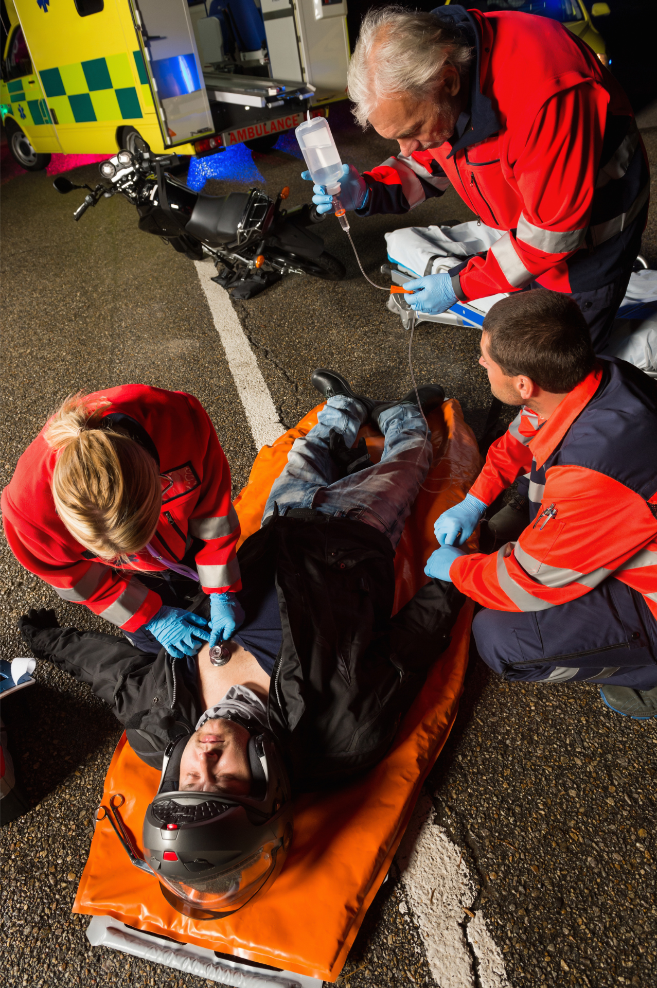 two firefighters are working on a motorcycle accident victim