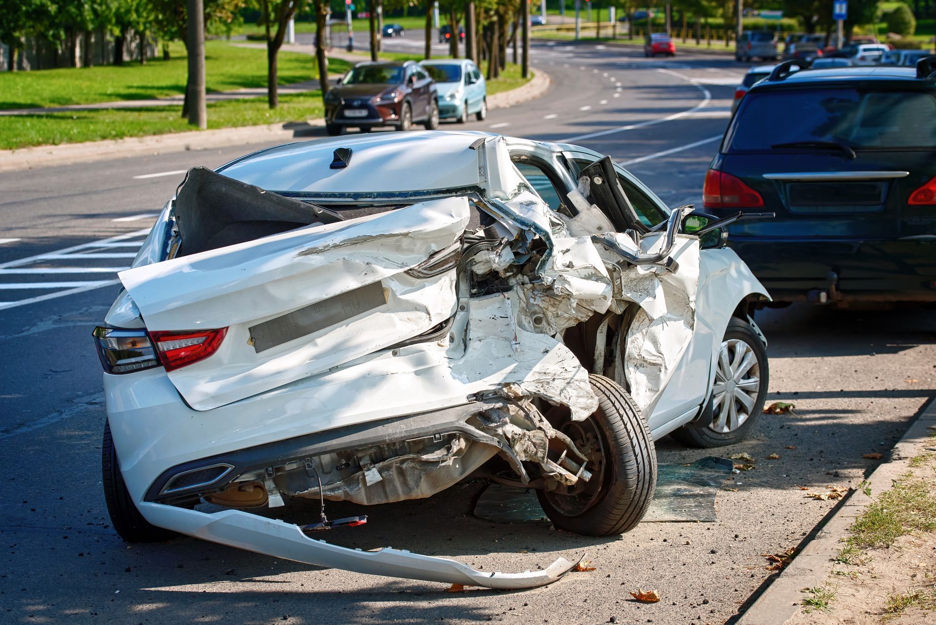 Severely damaged white sedan after a crash on a Merrillville street, with another car nearby.