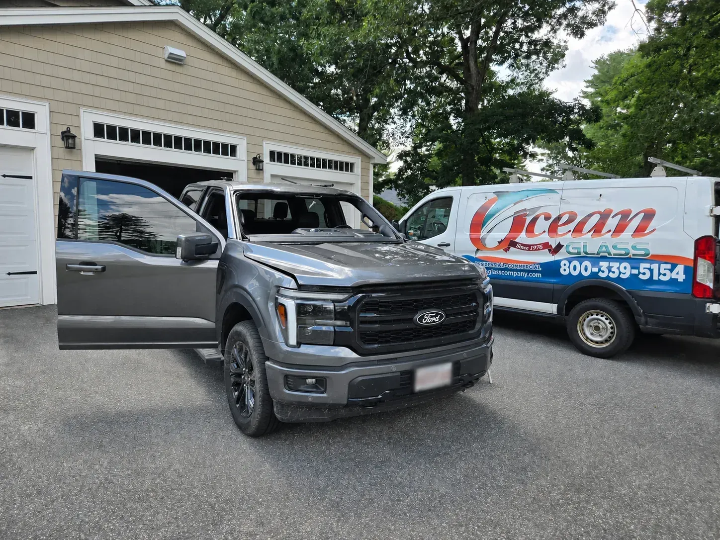 Ocean Glass service van behind a Ford pickup during windshield removal