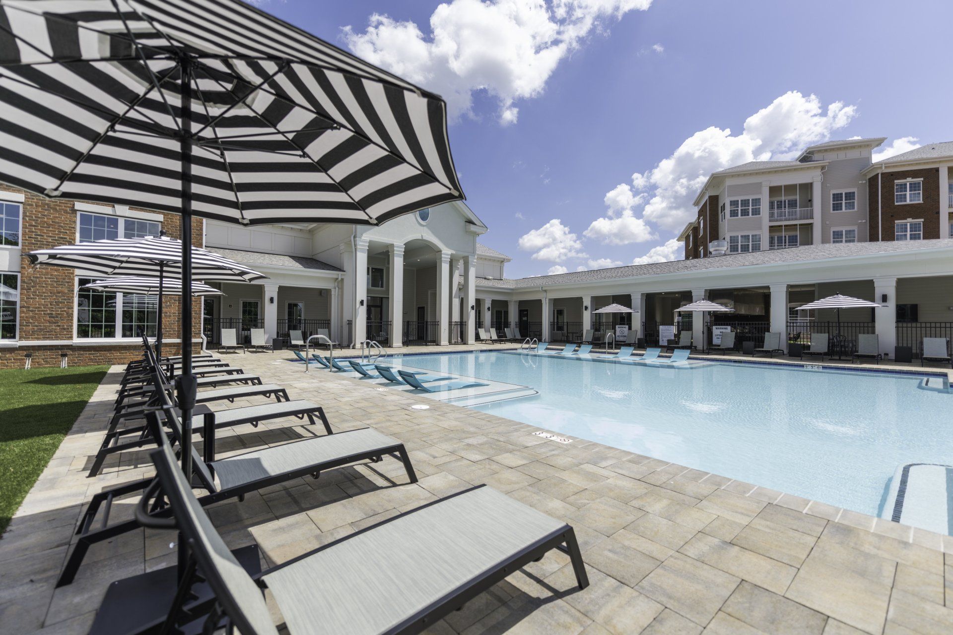 Silver Collection at Carl D. Silver Parkway resort-style pool with lounge chairs, umbrellas, and apartment buildings in Fredericksburg, VA.