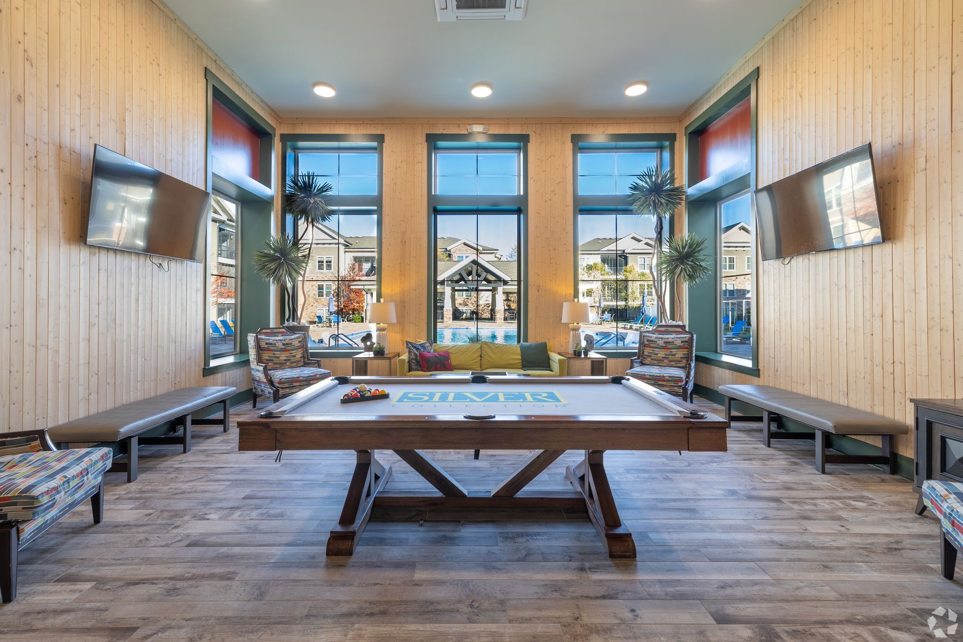Silver Collection at Cosner's Corner resident lounge with a game table, wood seating, and large windows overlooking Fredericksburg, VA.
