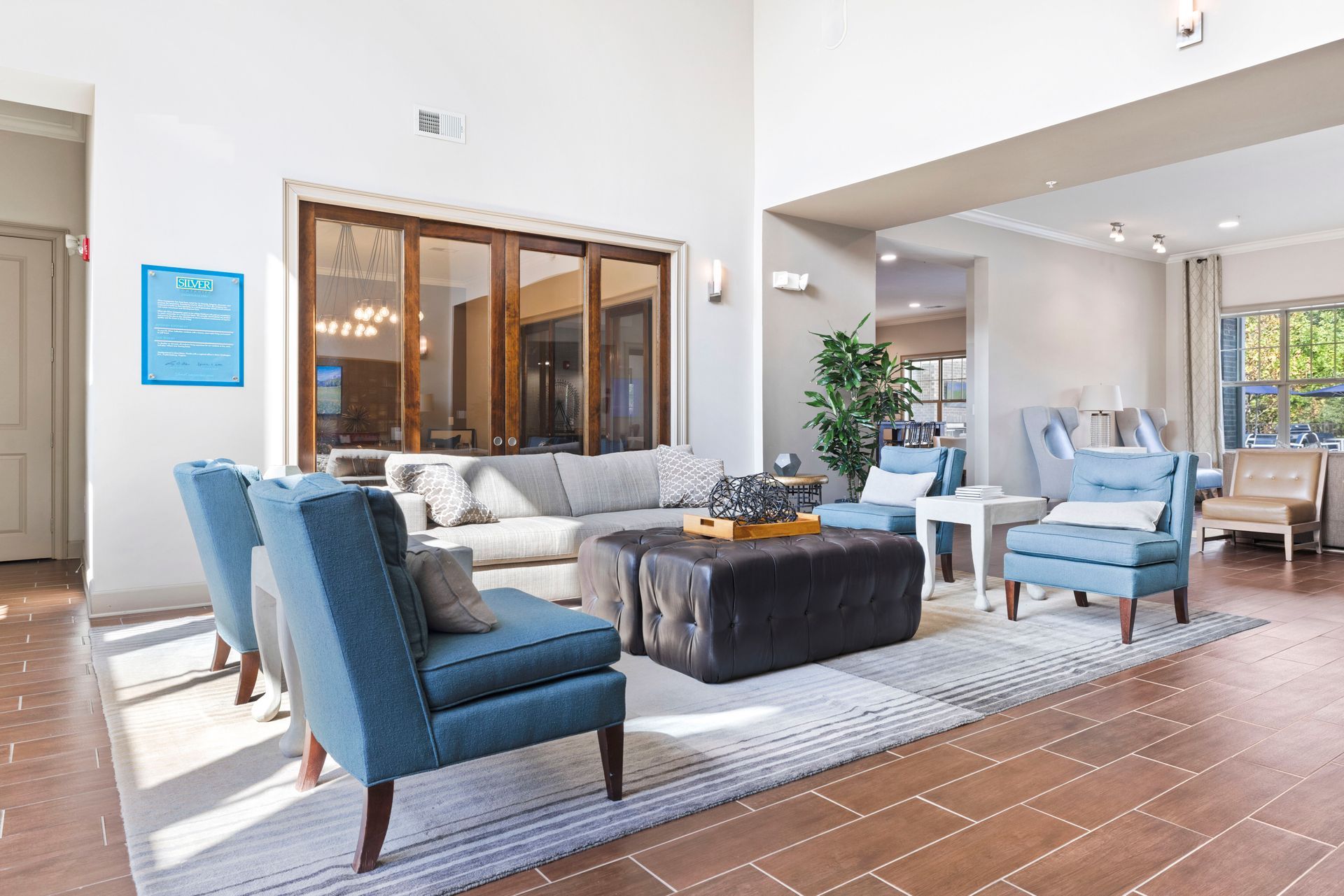 Silver Collection at Waterford resident lounge with blue seating, an ottoman, and large windows in Huntersville, NC.