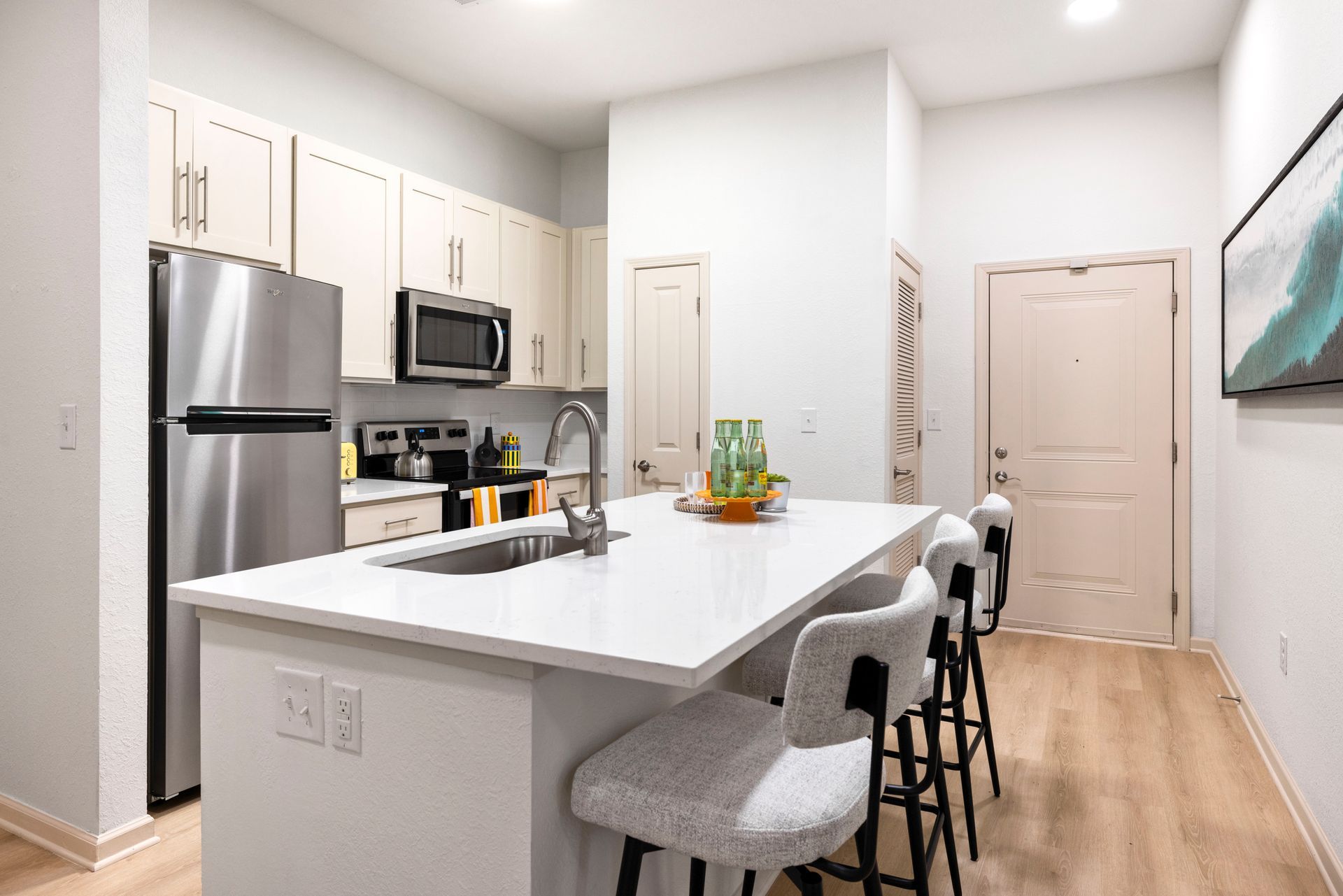 Silver Collection at Waterford apartment kitchen with white cabinets, stainless steel appliances, island seating, and wood flooring in Huntersville, NC.