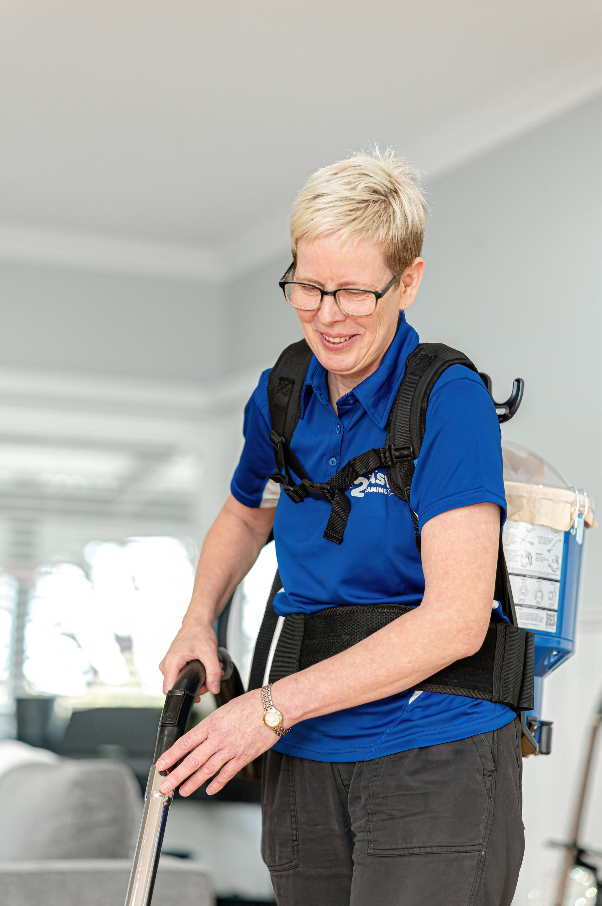 A Woman In A Blue Shirt Is Holding A Vacuum Cleaner — 2easy Cleaning in Bendigo, VIC