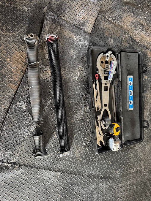 Coiled springs and a small tool kit laid out on a gray quilted surface.