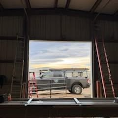 Van parked inside a large garage, seen through a wide open doorway at sunset