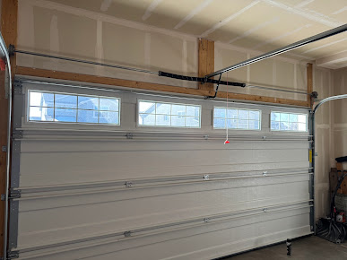Closed white garage door with four small windows in a beige garage interior