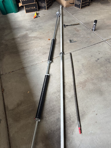 Two long fishing rods laid on a concrete floor, one black and one silver with red tip.