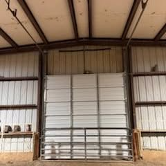 Metal warehouse interior with a large white roll-up door and metal railings in front