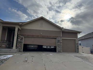 Suburban house with a two-car garage, driveway, and cloudy sky overhead
