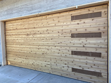 Wooden garage door with horizontal planks and three dark rectangular accents on the right