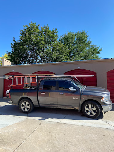 Gray pickup truck parked in front of red garage doors on a sunny driveway