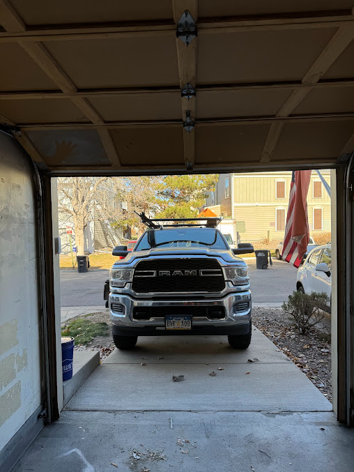 Silver pickup truck parked in a garage, viewed from inside toward the driveway.