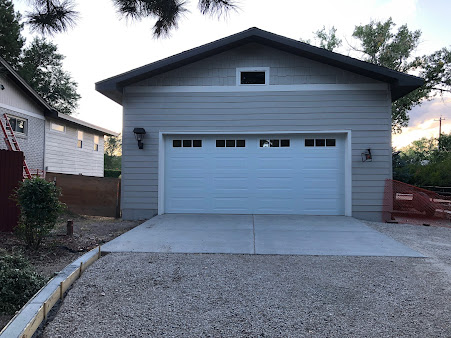 Single-story white house with a two-car garage and gravel driveway at dusk