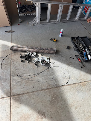 Workshop floor with scattered tools, wires, a ladder, and disassembled parts near a wall.