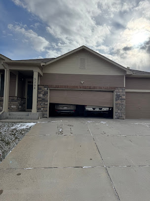 Suburban house with a two-car garage and a driveway under a cloudy sky.