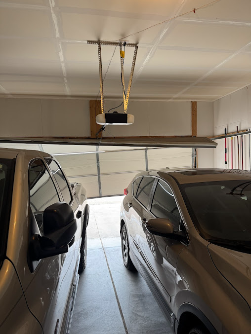 Two cars parked in a garage with a suspended lift mechanism overhead