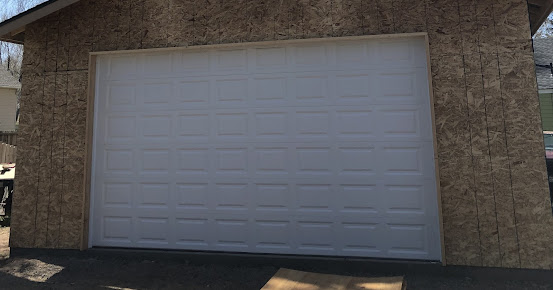 White garage door set in a tan stone building exterior.
