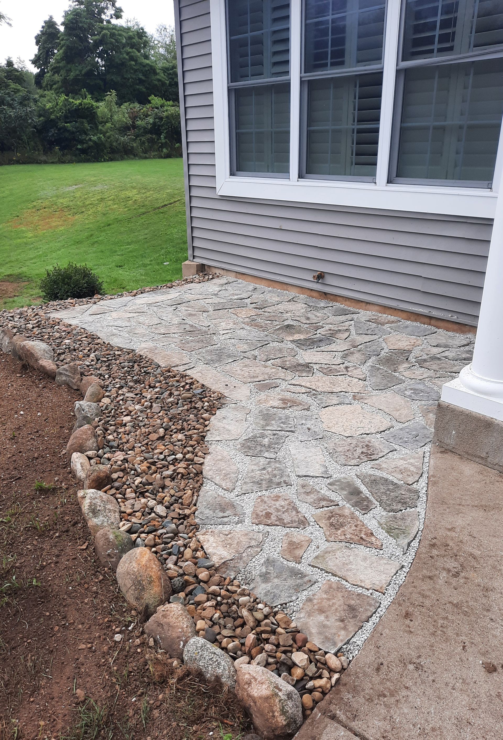 A stone walkway leading to a house with a window.