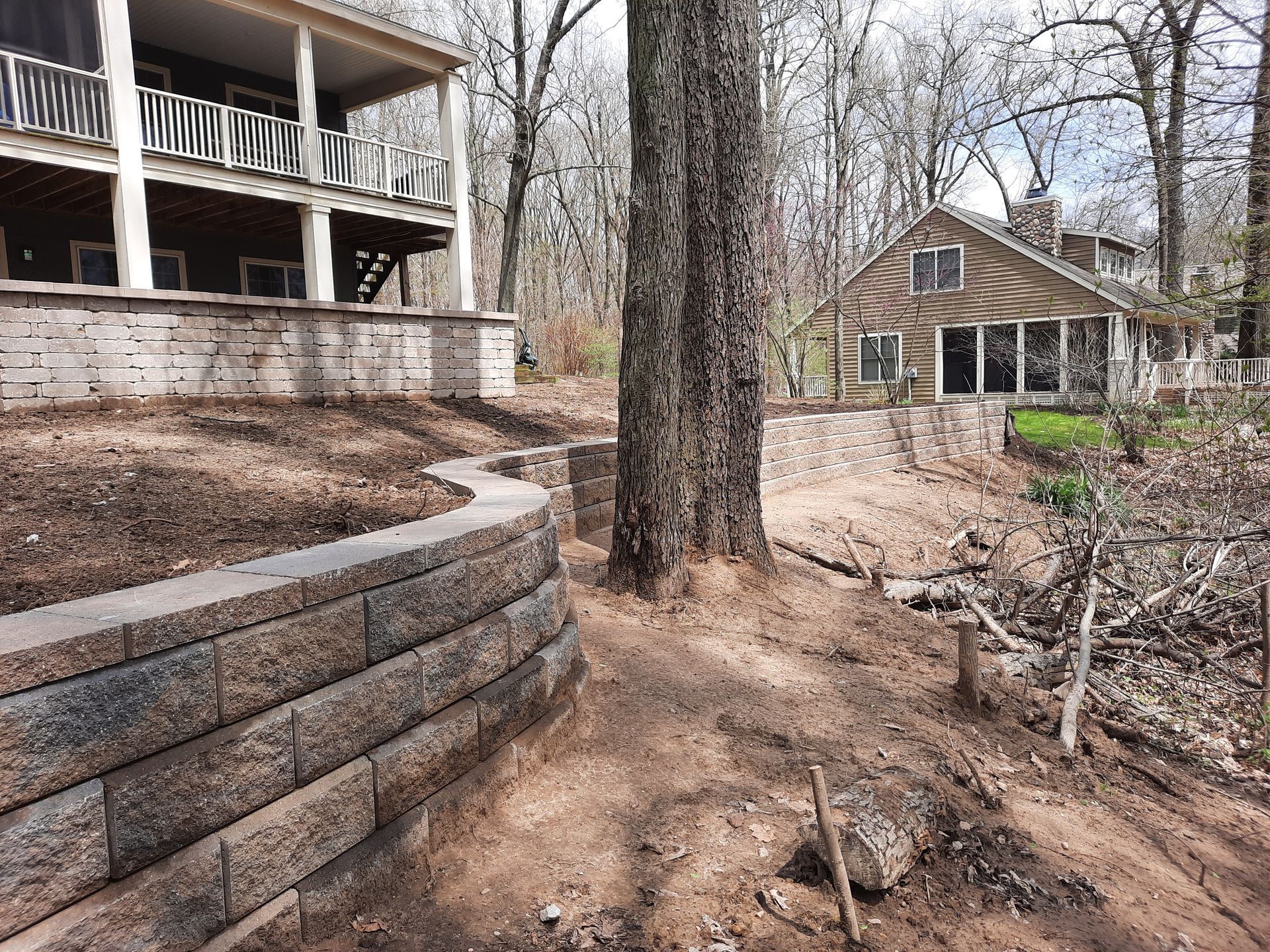 A house is sitting on top of a hill next to a tree.