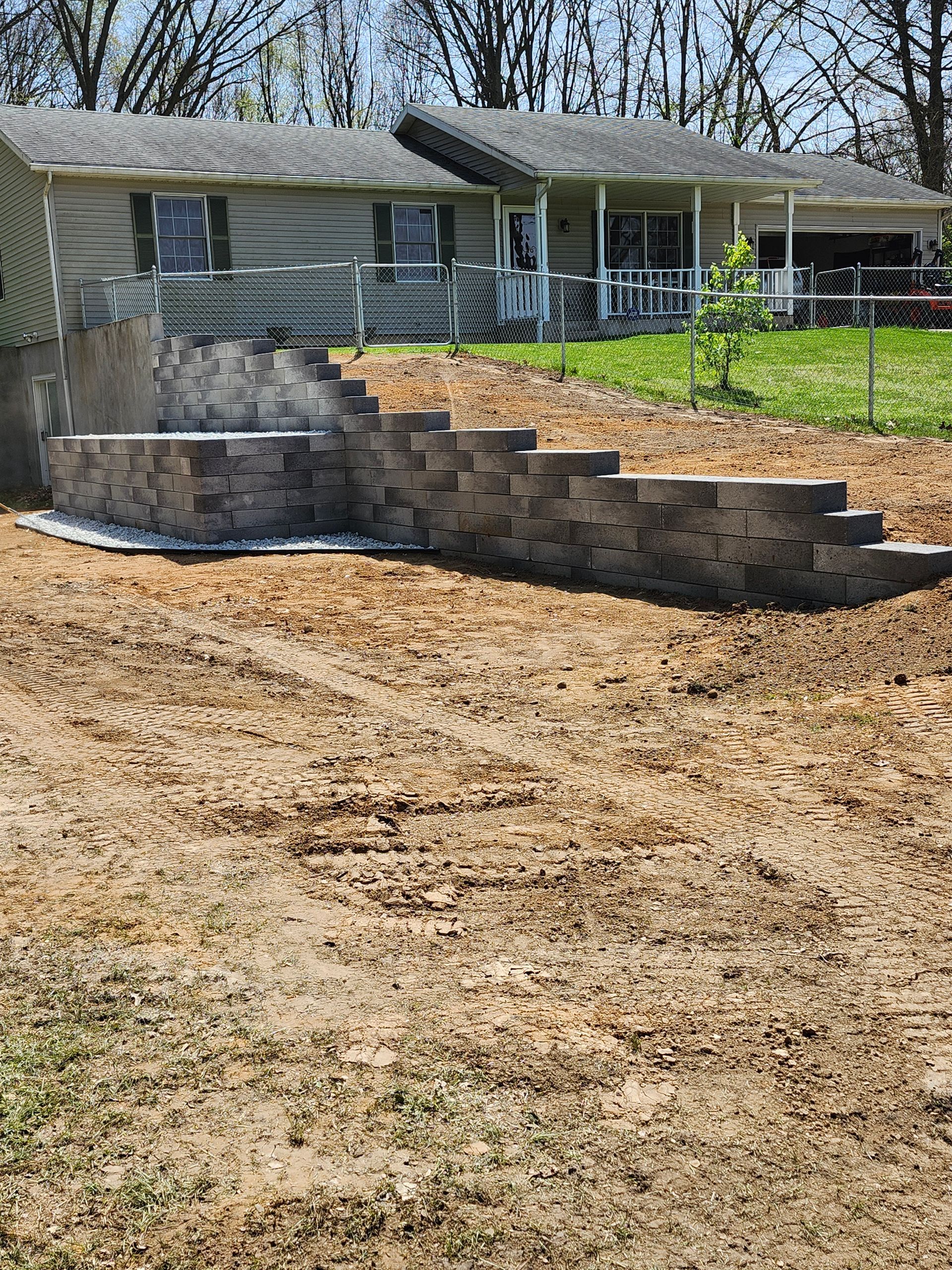 A brick wall is being built in the backyard of a house.