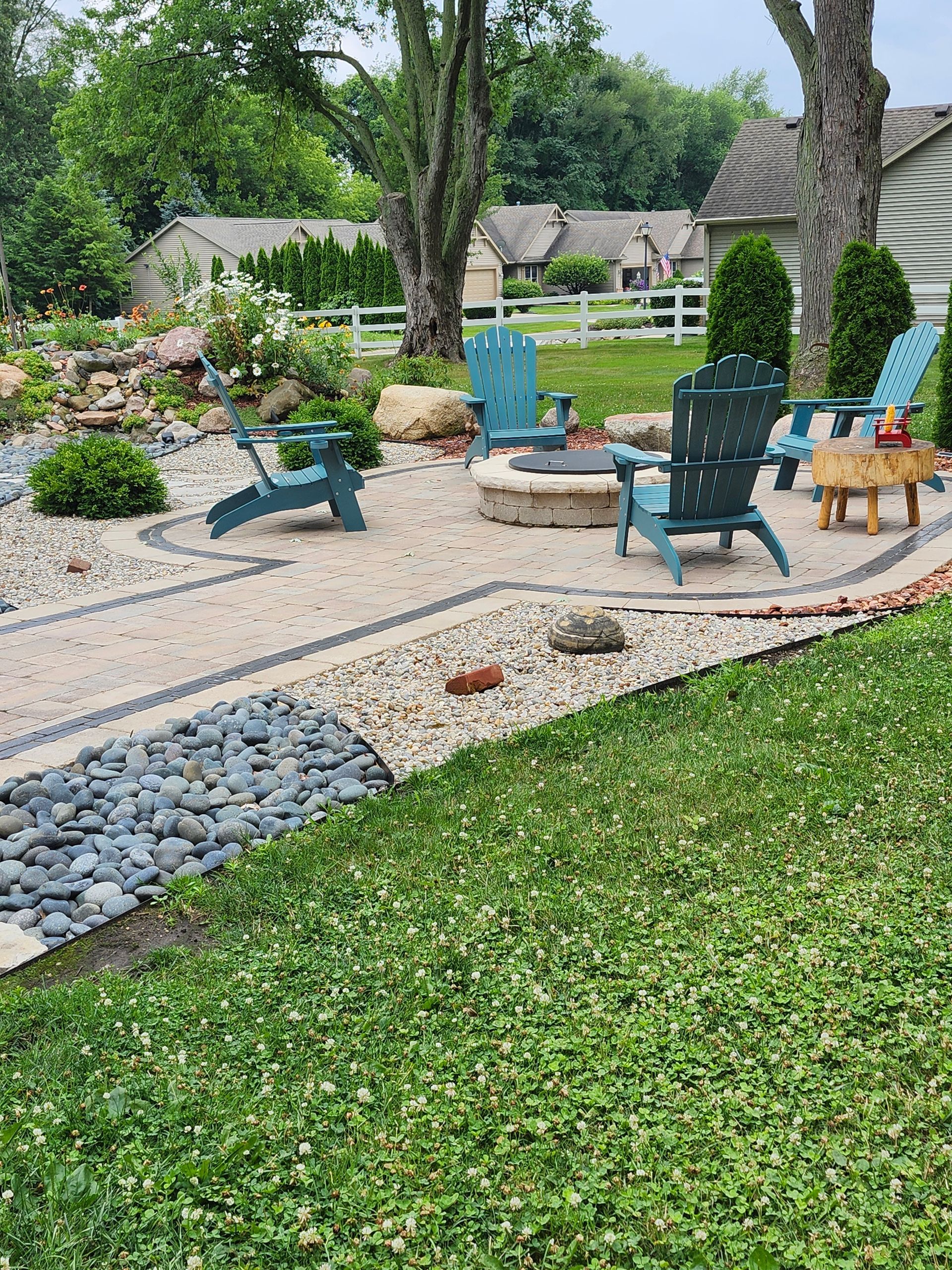 A patio with blue chairs and a fire pit in the backyard.