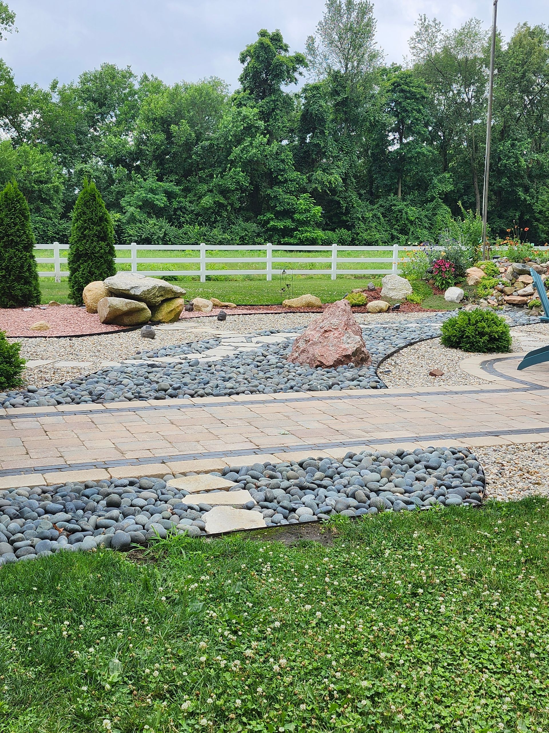 There is a fence in the background and a brick walkway in the foreground.