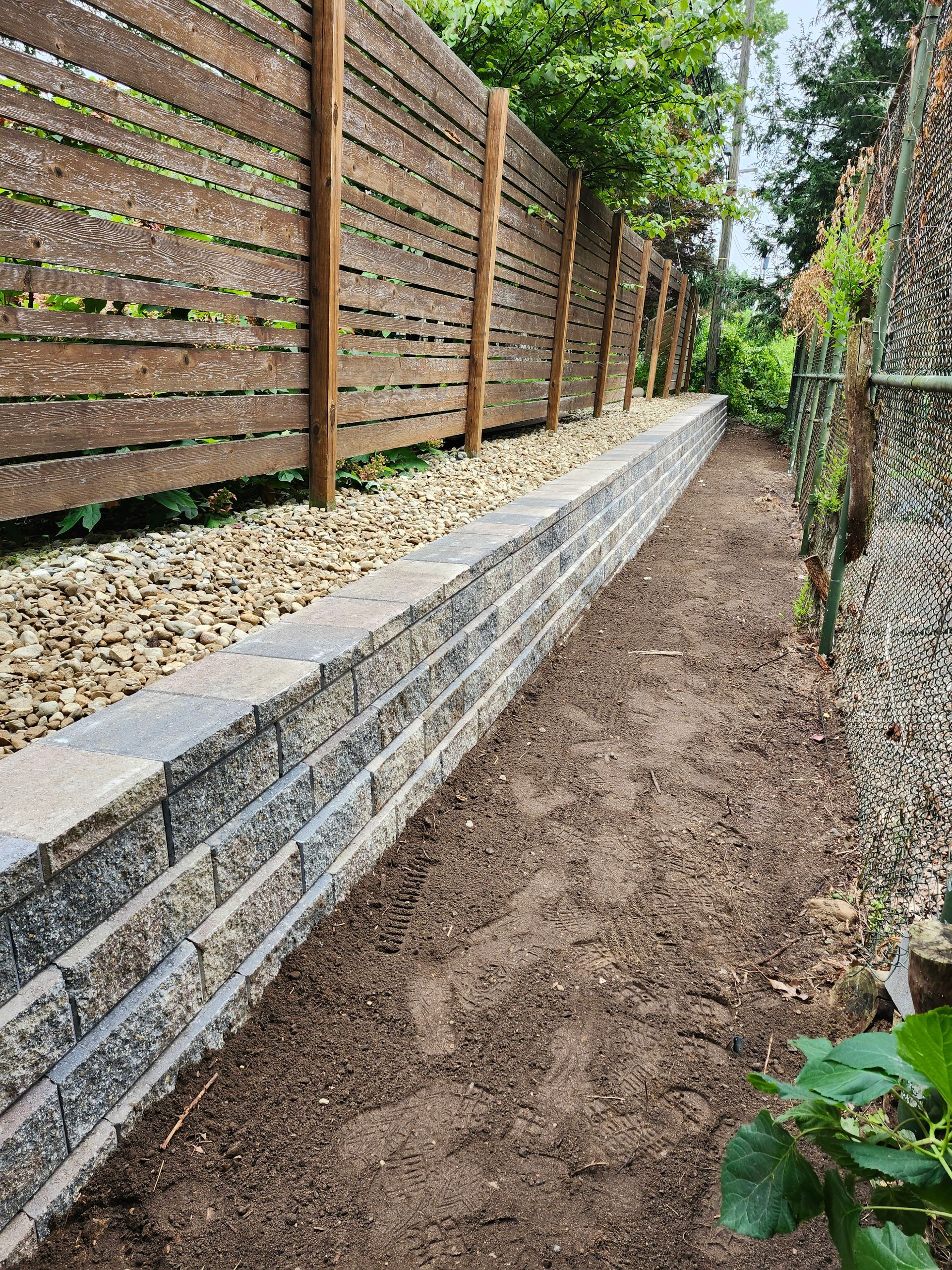 A stone wall with a wooden fence in the background.