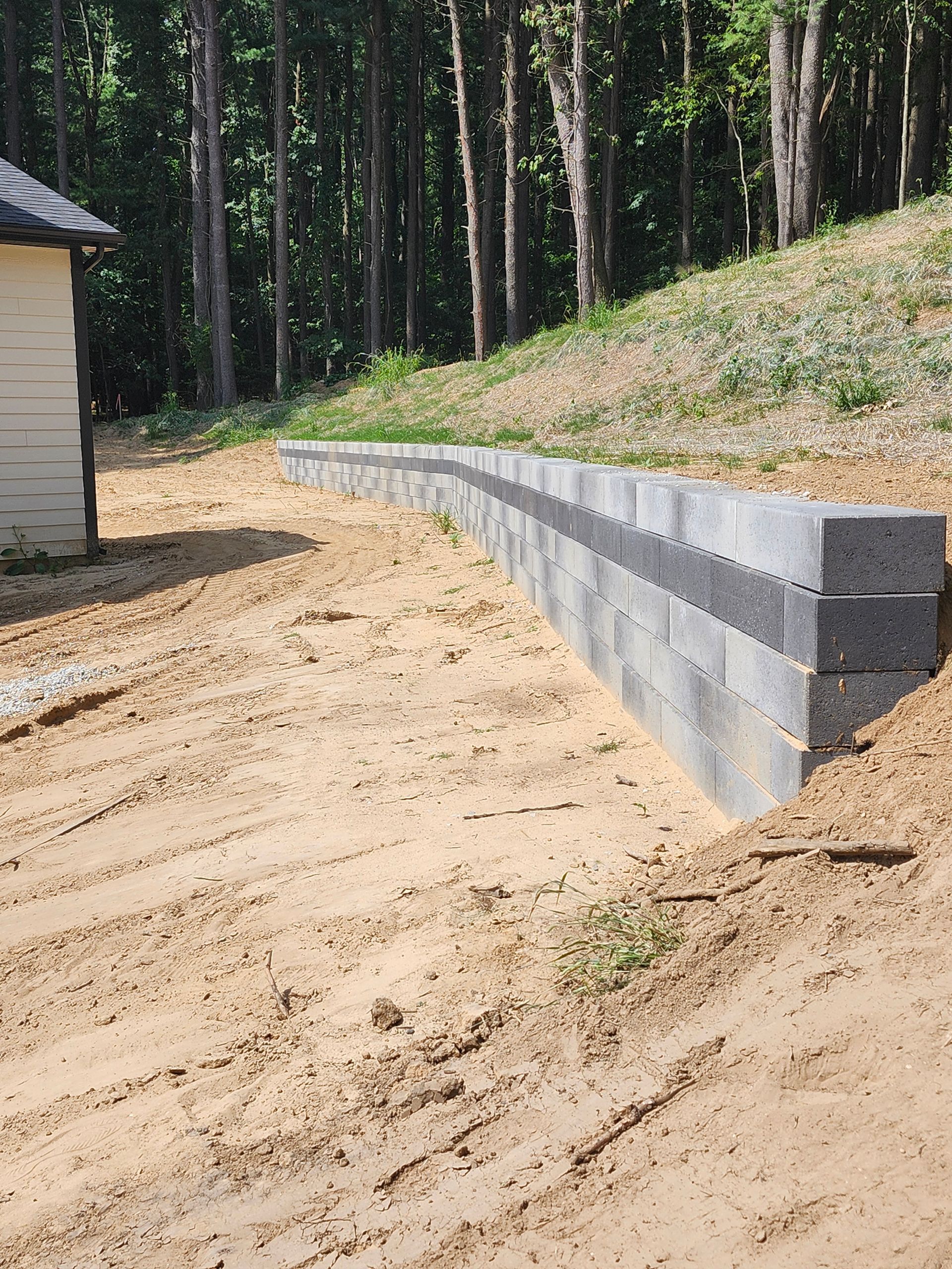 A concrete wall is being built on a dirt hillside