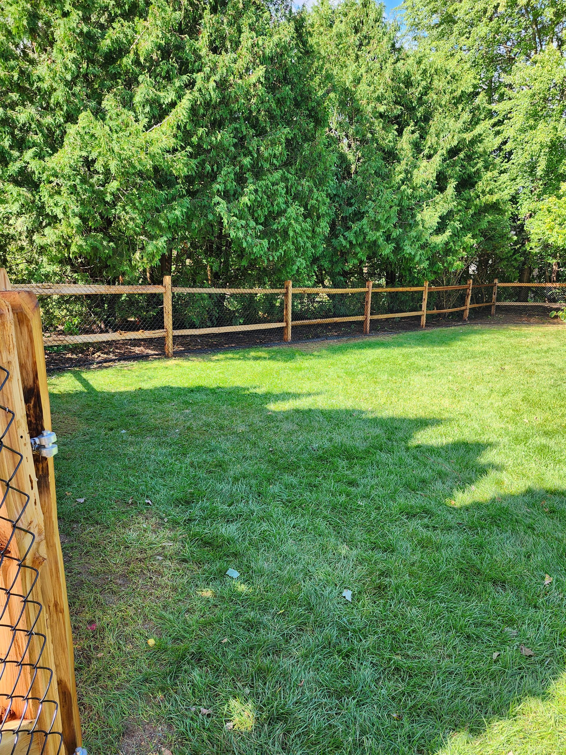 A wooden fence surrounds a lush green yard.