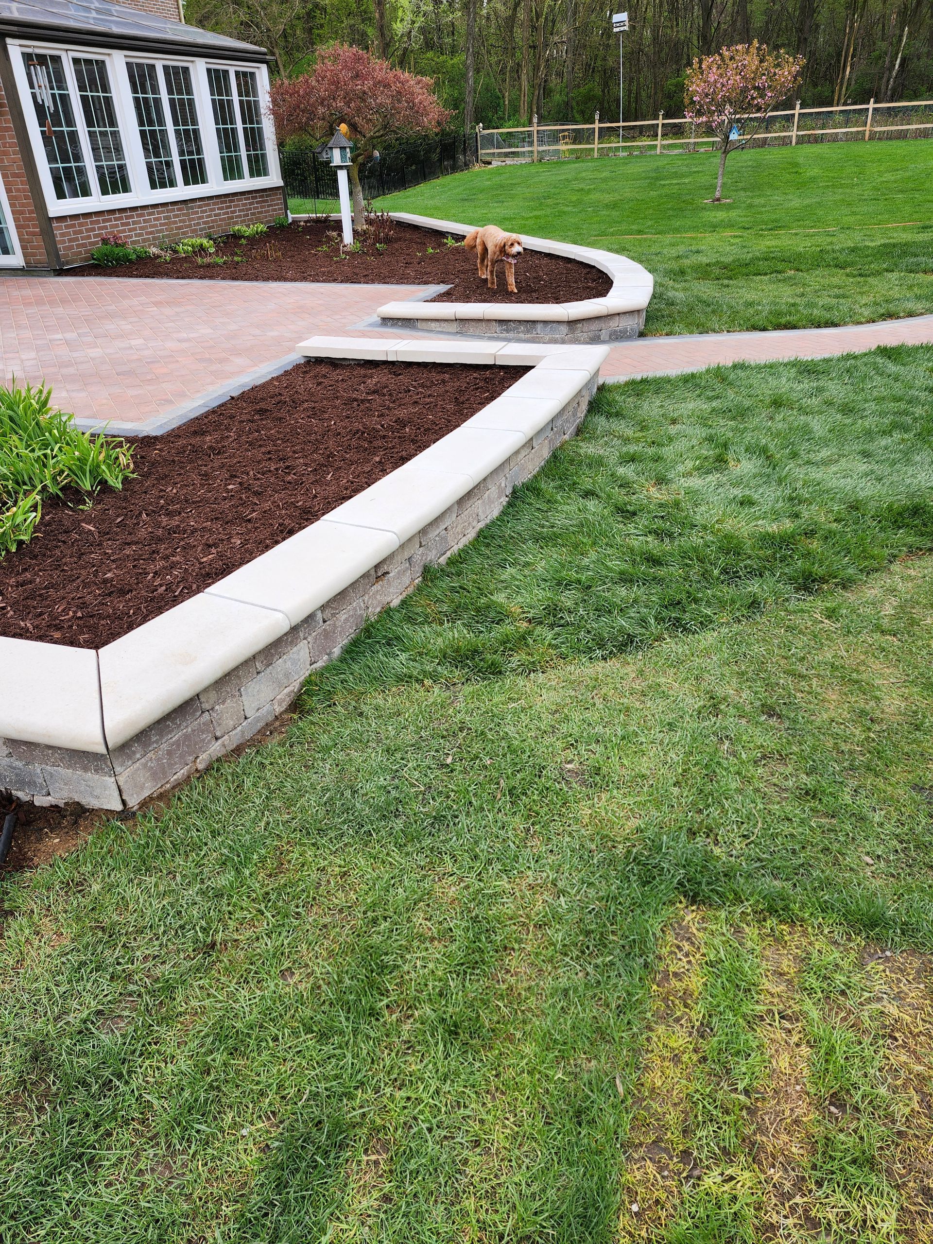 A lush green lawn with a brick walkway leading to a house.