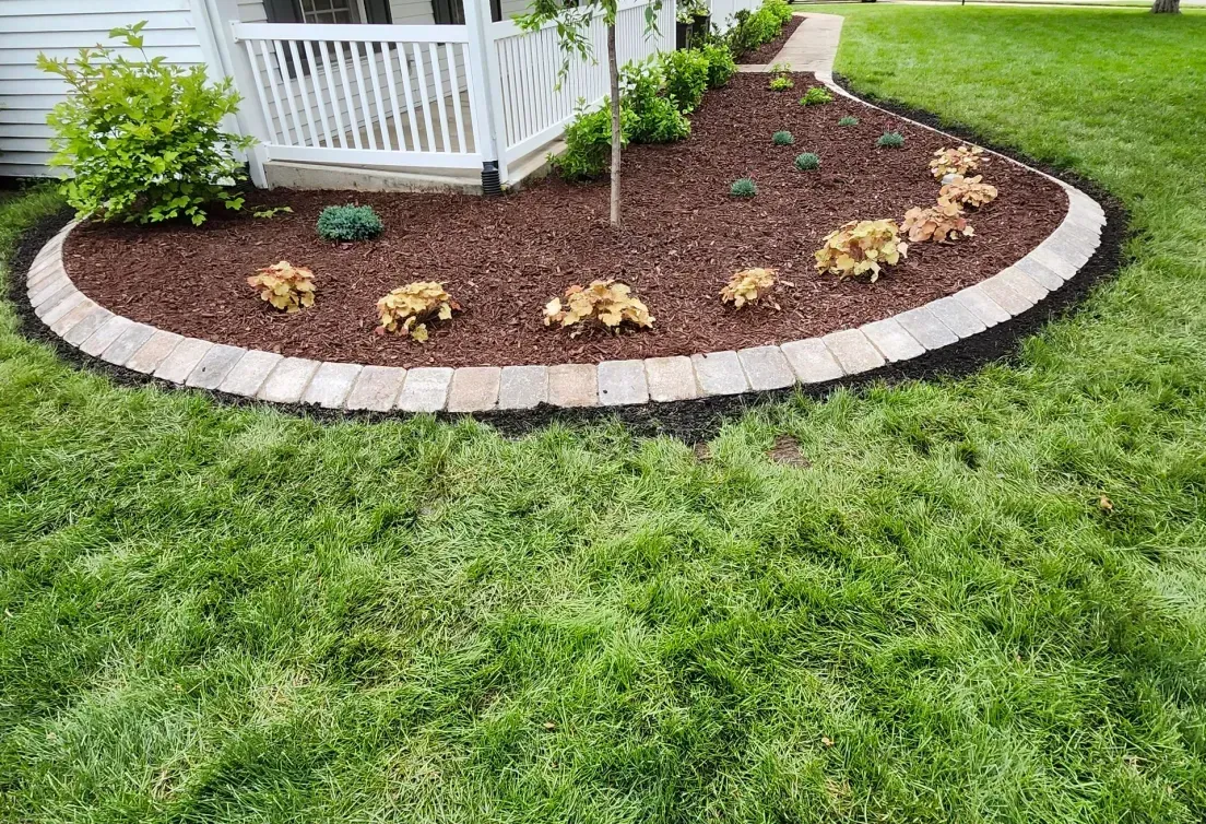 A lush green lawn with a circular garden in front of a house.