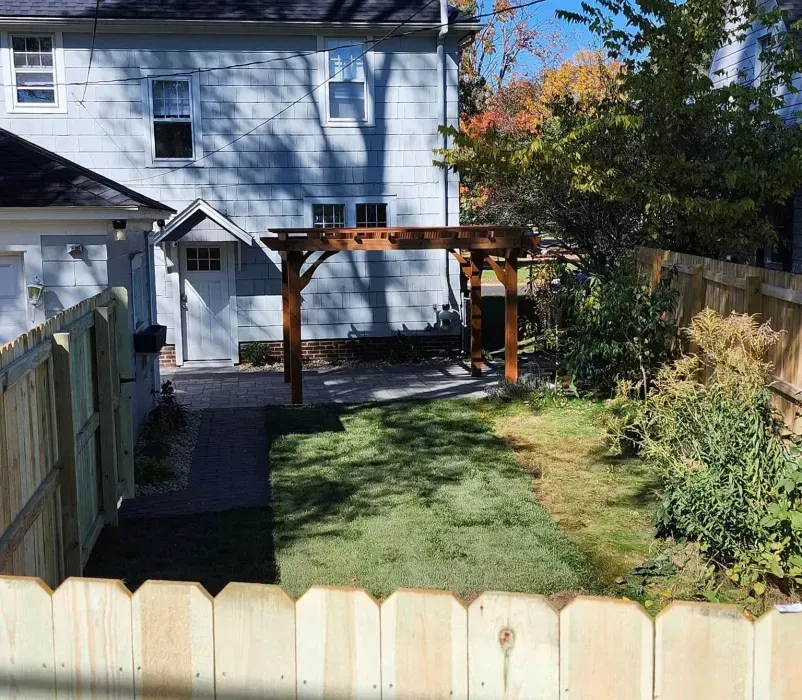 A backyard with a wooden fence and a house in the background.