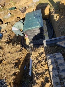 Worker stacking plastic crates beside a trench in a dirt yard