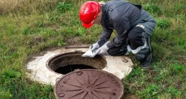 Worker in red hard hat cleaning a manhole opening outdoors