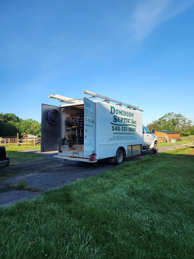 White moving truck parked on a grassy roadside under a blue sky, rear door open.