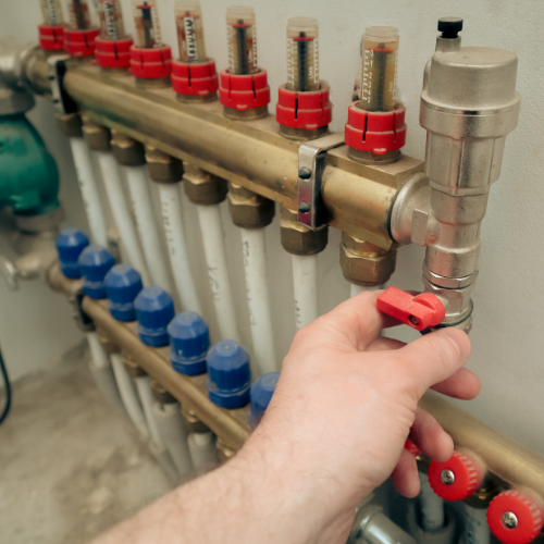A person is adjusting a valve on a heating system