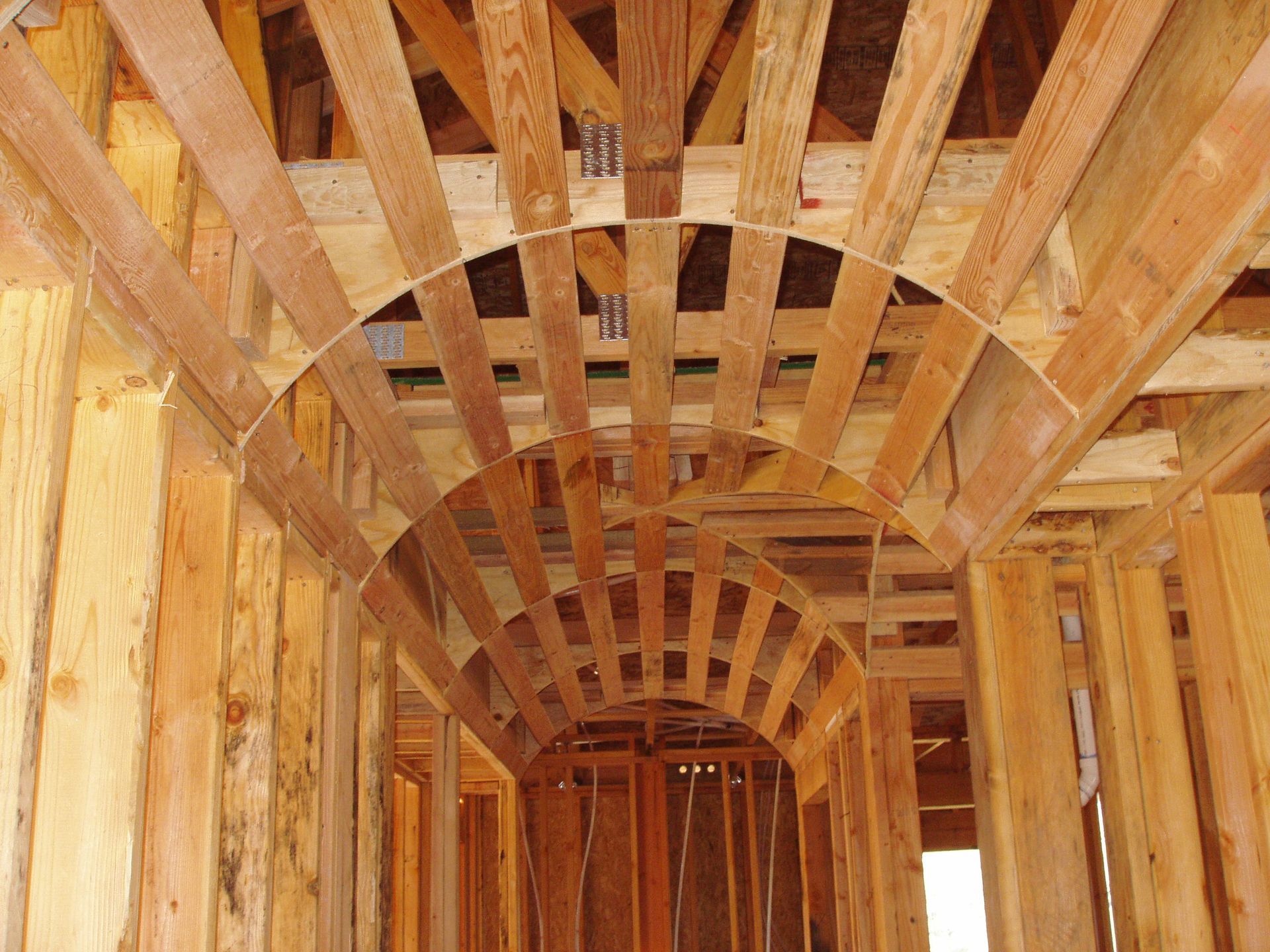 Wooden house frame under construction, showcasing an arched ceiling design.