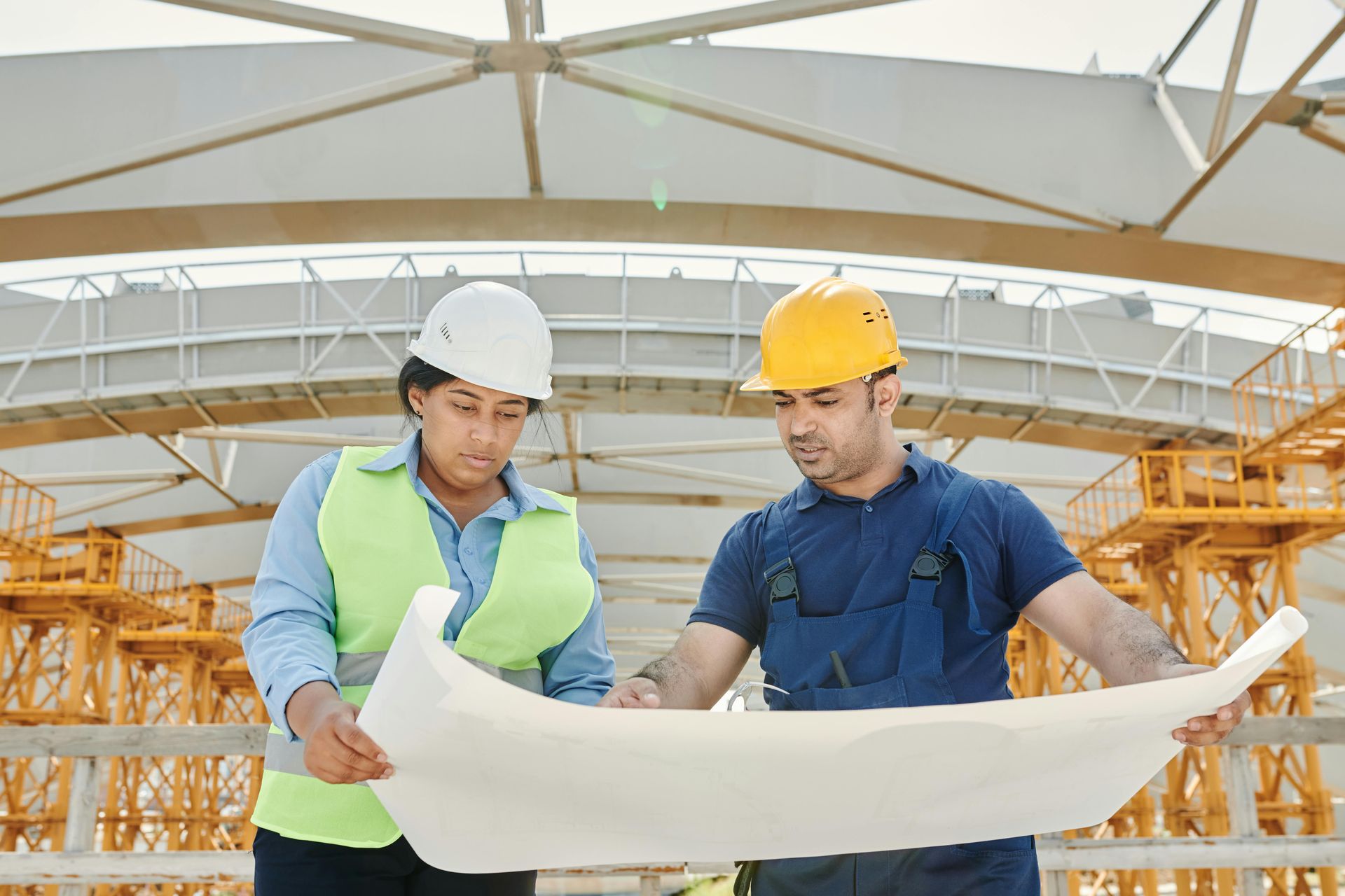 Two construction workers reviewing blueprints on a building site.