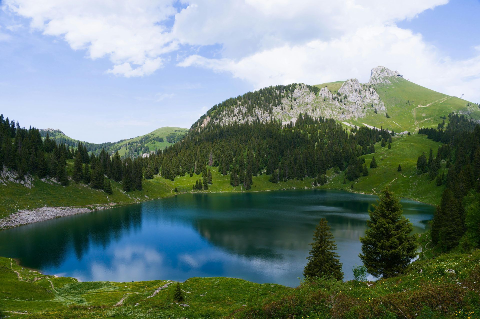 Ein zugefrorener See spiegelt die Berge unter einem klaren blauen Himmel; weißer Schnee bedeckt die Berggipfel.