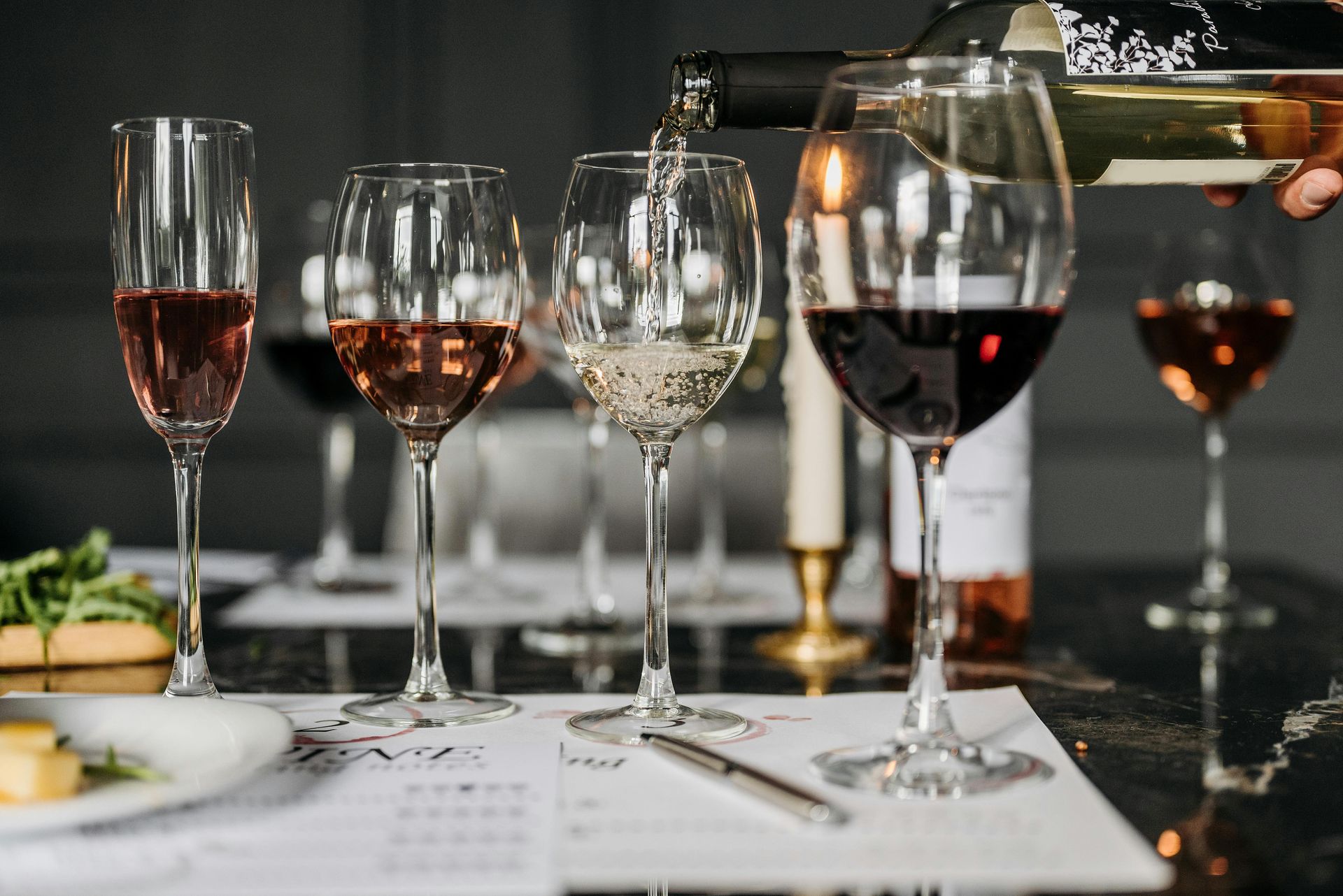 Wine glasses and table settings at a candlelit dinner table with red wine and hors d'oeuvres