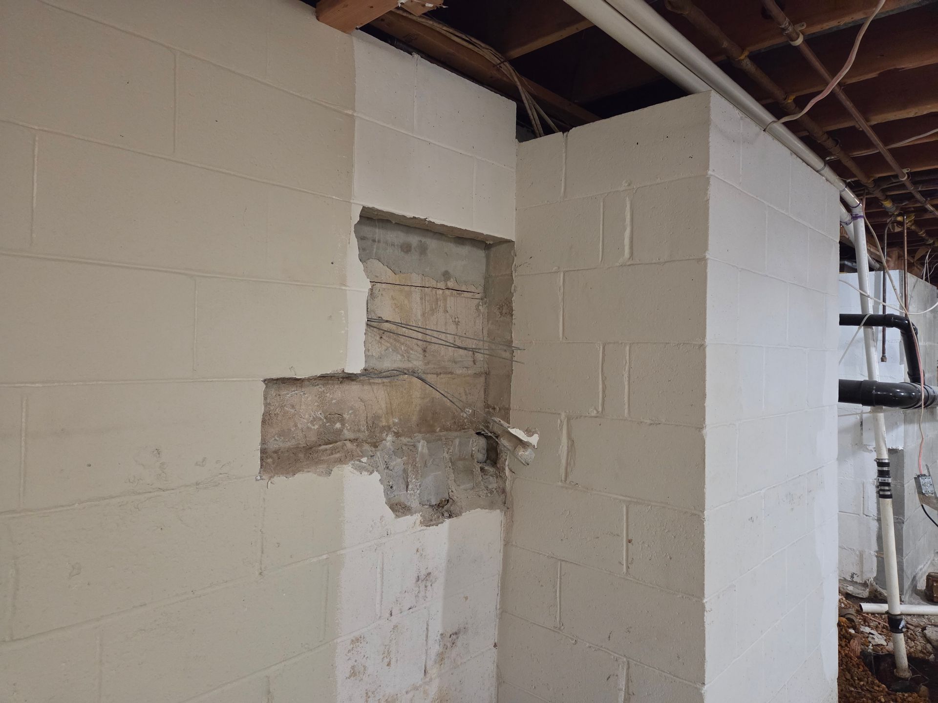 A professional in a high-visibility vest inspects a cracked wooden beam in an attic using a tablet.