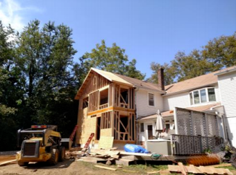 A house under construction with a yellow bulldozer in front of it