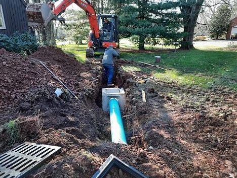 A man is digging a hole in the ground to install a pipe.