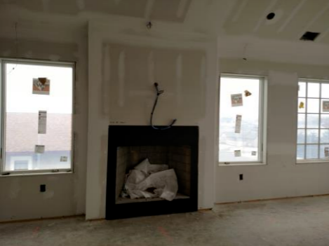 An empty living room with a fireplace and windows