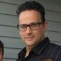 A man wearing glasses and a black shirt is standing next to a child.
