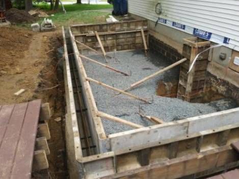 A concrete foundation is being built next to a house.